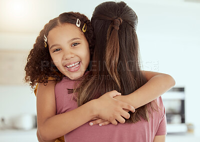Portrait of mixed race single mother and daughter hugging in living room at home. Smiling hispanic girl embracing single parent and bonding in lounge. Happy affectionate child and woman on a weekend