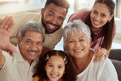 Portrait of mixed race family with child taking selfies in living room at home. Adorable smiling hispanic girl bonding with grandparents, mother and father. Happy couples and child sitting together