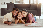 Portrait of mixed race parents enjoying weekend with cute daughter in home living room. Smiling hispanic girl bonding with mother and father in lounge. Happy couple lying together with kid on weekend