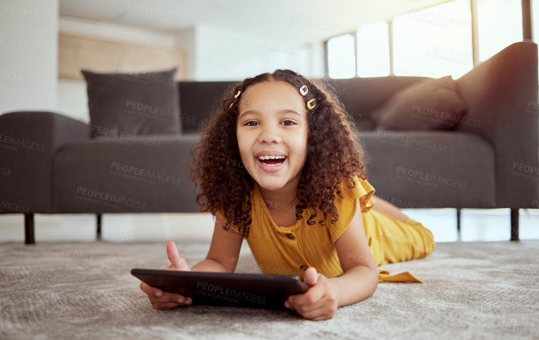 Buy stock photo Portrait of adorable little mixed race child using digital tablet in home living room. One small cute hispanic girl lying alone on lounge floor, playing game on technology. Happy kid with curly hair