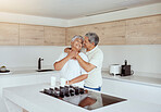 Mixed race senior couple hugging in the morning at home. Smiling elderly husband and wife holding each other and embracing in kitchen. Happy retired ethnic man and woman bonding and feeling in love