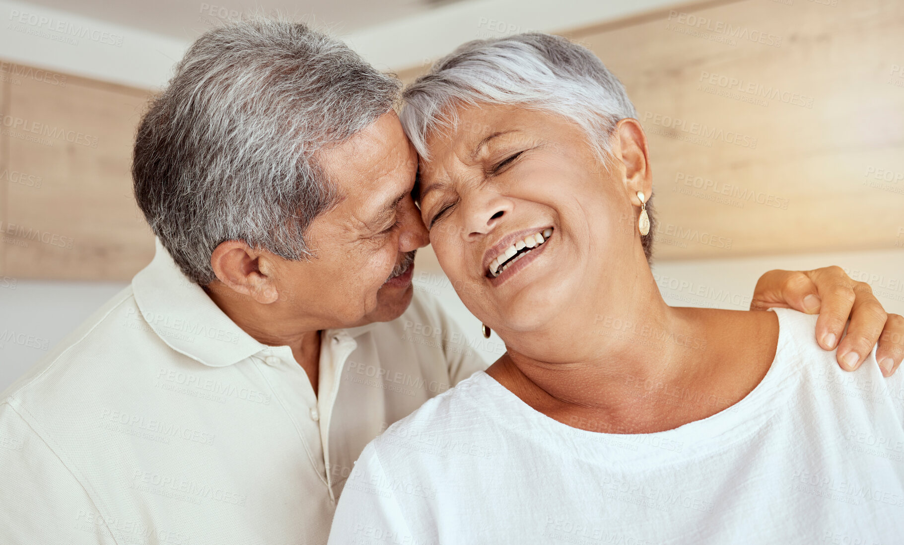 Buy stock photo Mixed race senior couple hugging in the morning at home. Smiling elderly husband and wife holding each other and embracing in kitchen. Happy retired ethnic man and woman bonding and feeling in love
