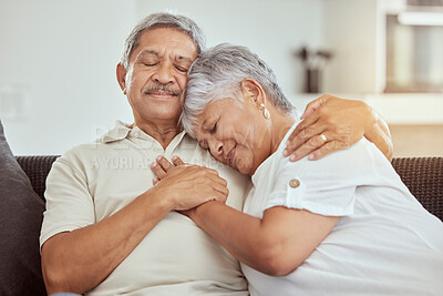 Mixed race senior couple hugging in a living room at home. Smiling elderly husband and wife holding each other on sofa and embracing in lounge. Happy retired man and woman bonding and feeling in love