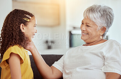 Buy stock photo Mixed race grandmother and granddaughter in living room at home. Smiling senior woman enjoying weekend with adorable little girl in lounge. Happy hispanic child bonding and sitting with grandparent