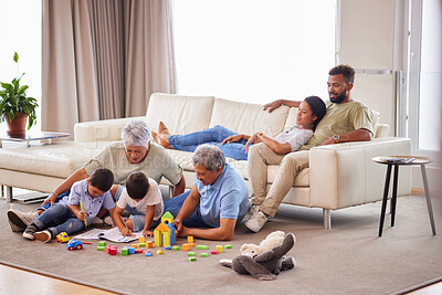 A mixed race family bonding together while grandparents playing with the grandkids while the adult parents relax on the couch at home