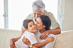 Happy mature grandmother relaxing with her grandson and adult daughter at home. Cheerful little hispanic boy sitting on the couch together with his mother and grandmother