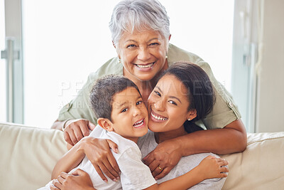 Happy mature grandmother relaxing with her grandson and adult daughter at home. Cheerful little hispanic boy sitting on the couch together with his mother and grandmother