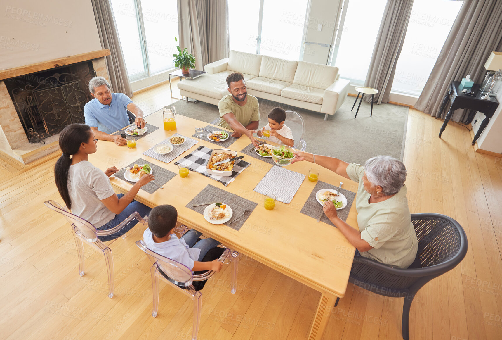 Buy stock photo Overhead view of a mixed race family sitting at a table having lunch  in the lounge at home. Hispanic grandparents having a meal with their kids and grandkids at home