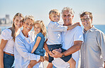 Portrait of happy caucasian multi-generation family standing together at the beach on a sunny day. Two little children enjoying time at the beach with their parents and grandparents