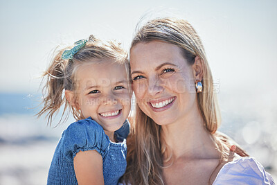 Buy stock photo Portrait of a happy mother and little girl bonding and having fun at the beach while on vacation. Loving caucasian woman holding her daughter while spending time together outdoors