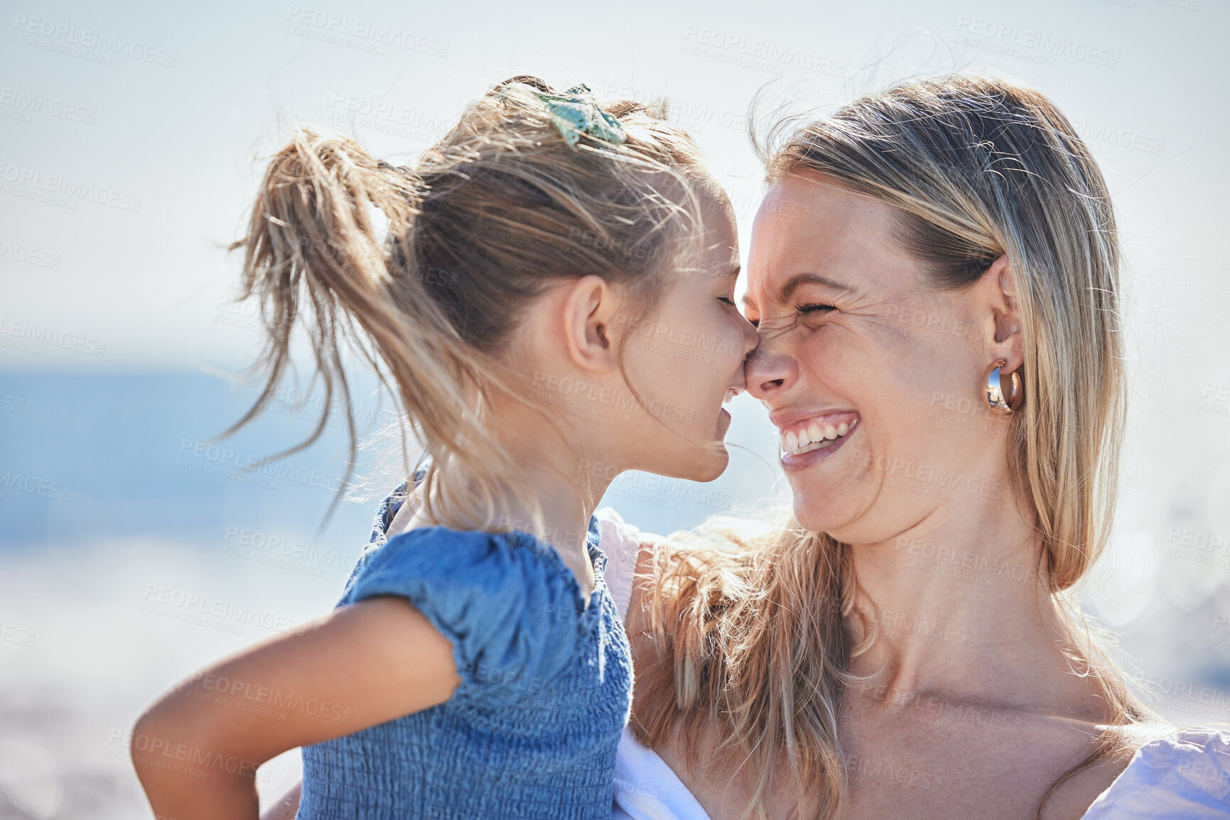 Buy stock photo Adorable little daughter and mother rubbing noses while spending time together at the beach while on vacation. Cheerful mom and little girl having fun outdoors on a sunny day