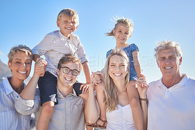 Buy stock photo Portrait of happy caucasian multi-generation family standing together at the beach on a sunny day. Two little children enjoying time at the beach with their parents and grandparents against a blue sky