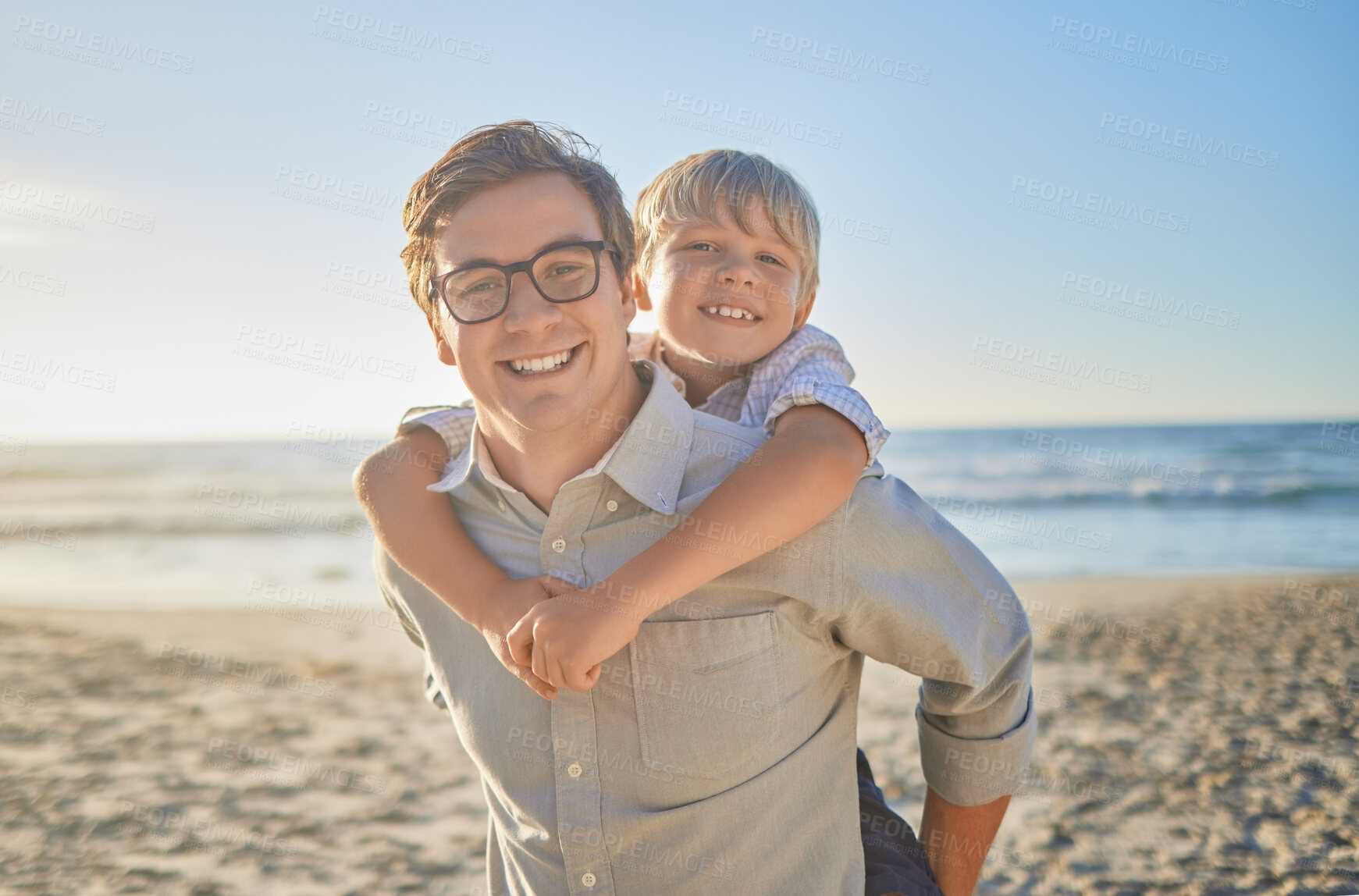 Buy stock photo Portrait of smiling caucasian father carrying little son on his shoulders on a beach with. Adorable, happy, white boy bonding with single parent outside on weekend. Man and child enjoying free time