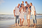 Portrait of a senior caucasian couple at the beach with their children and grandchild. Happy family relaxing on the beach having fun and bonding