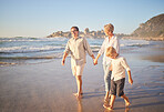 Cute caucasian girl being held outside by her dad and grandmother in the sea at the beach. A young man and his mom holding his cute daughter while walking in the water on the coast at sunset