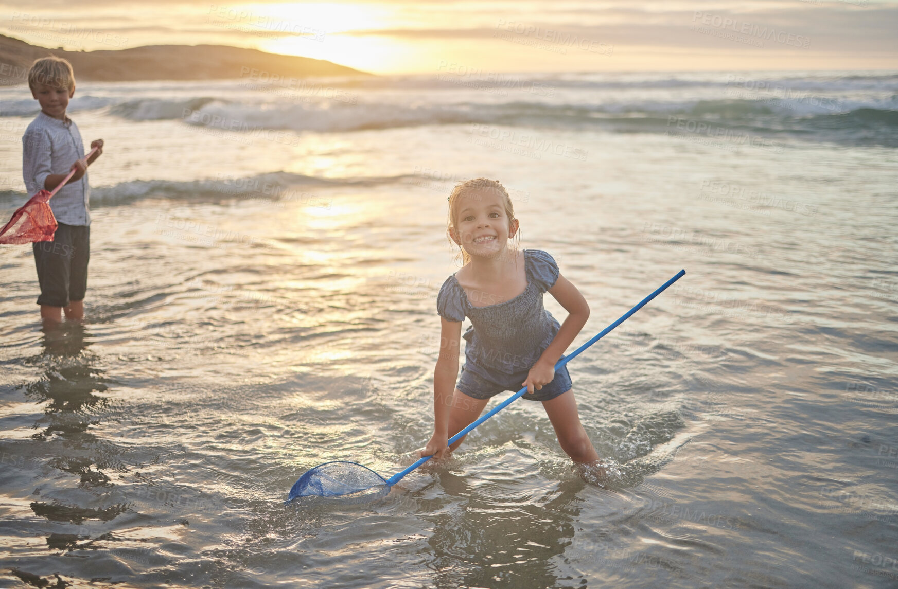 Buy stock photo Portrait of a cute caucasian  little girl and her brother playing in the water with nets at the beach during summer on vacation