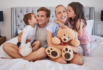 Buy stock photo Loving children sharing tender moment with parents while gently kissing mom and dad on the cheek. Happy caucasian parents spending time with their little daughter and son at home in the morning