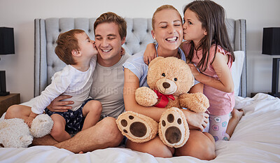 Loving children sharing tender moment with parents while gently kissing mom and dad on the cheek. Happy caucasian parents spending time with their little daughter and son at home in the morning