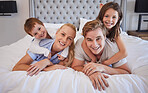 Portrait of a cheerful family lying together on bed. Little boy and girl lying on their parents laughing and having fun. Caucasian couple bonding with their son and daughter. Siblings enjoying free time with their mother and father