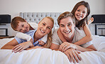 Portrait of a cheerful family lying together on bed. Little boy and girl lying on their parents laughing and having fun. Caucasian couple bonding with their son and daughter. Siblings enjoying free time with their mother and father