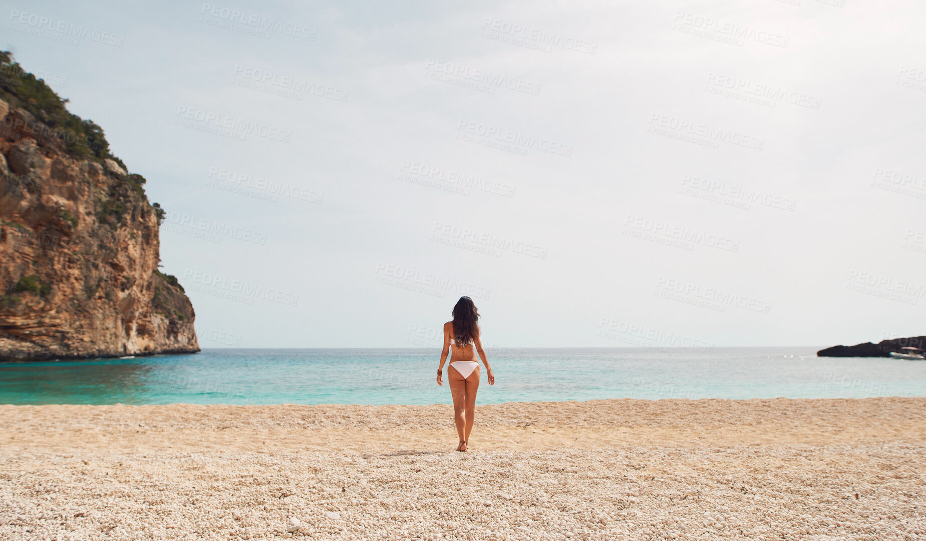 Buy stock photo Rear view, woman and bikini on beach in summer for holiday, vacation or swimming with sky and rock. Person, walking and swimwear on sand by ocean or sae for relax, peace and freedom outdoor in nature