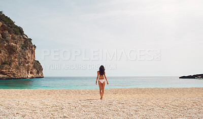 Buy stock photo Rear view, woman and bikini on beach in summer for holiday, vacation or swimming with sky and rock. Person, walking and swimwear on sand by ocean or sae for relax, peace and freedom outdoor in nature