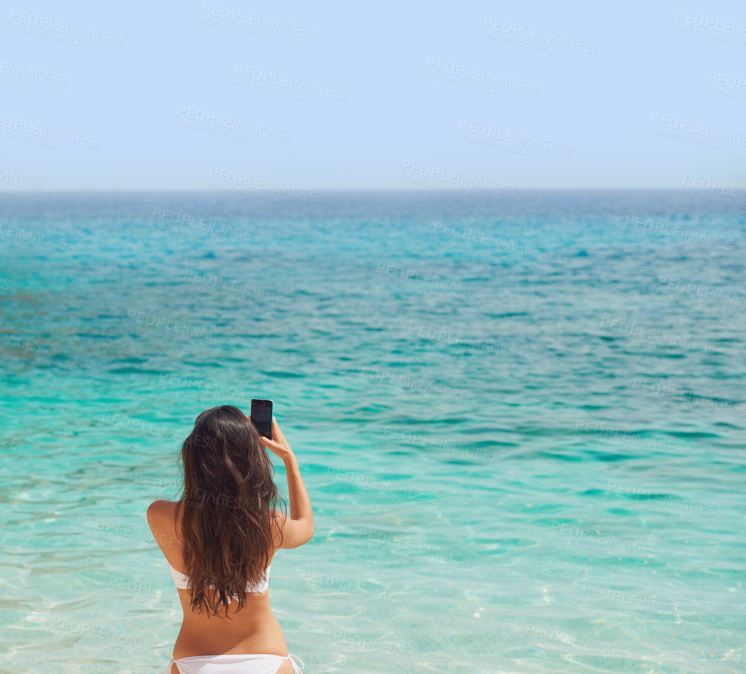 Buy stock photo Woman, bikini and phone by ocean in back view for social media, post or profile picture of tropical vacation. Female person, mobile or holiday for travel, island or Hawaii for wellness, care or relax
