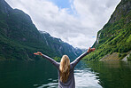 Travel adventure woman celebrates arms raised  at view of majestic glacial valley fjord lake on exploration discover beautiful earth