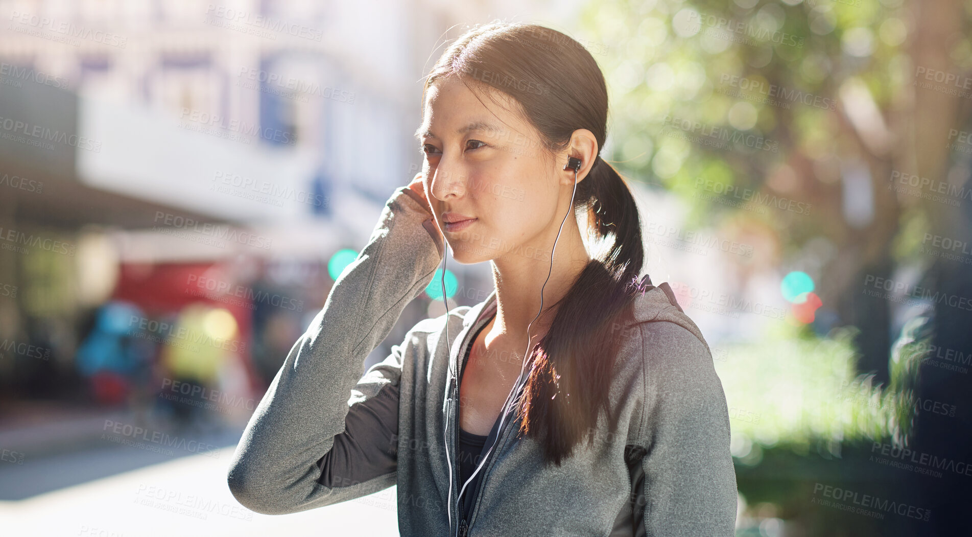 Buy stock photo Asian woman, earphones and music streaming while in the city for travel, exercise or run on a sunny day. Calm female listening to podcast, radio or audio on an urban street or sidewalk in summer