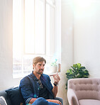 Attractive man using smartphone having phone call sitting on sofa at home