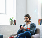 Young man using smartphone at home texting  reading social media messages browsing online