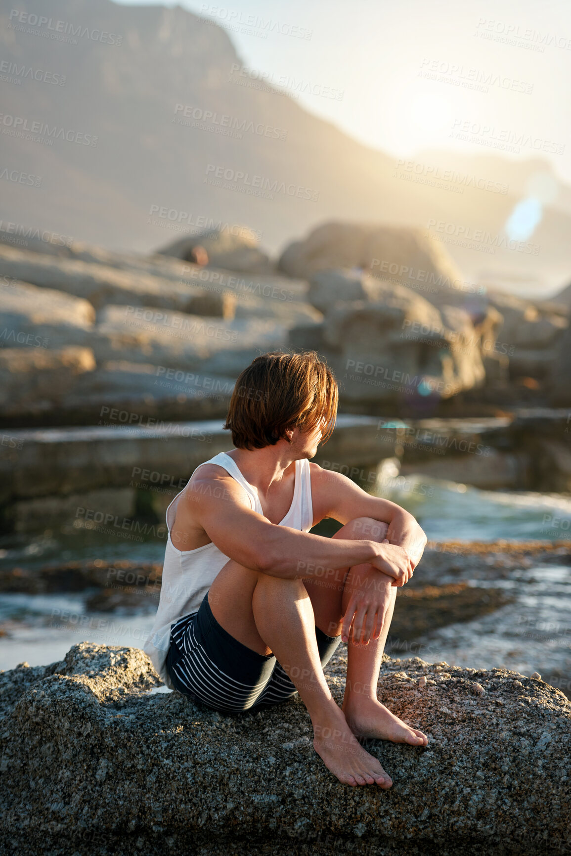 Buy stock photo young man sitting on beach looking at sunset watching ocean contemplating journey