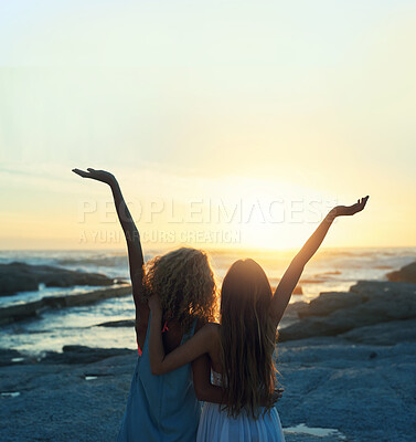 Buy stock photo two woman friends on beach celebrating with arms raised looking at sunset enjoying travel freedom lifestyle