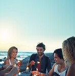 friends with sparklers celebrating new years eve on beach at sunset