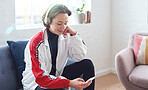 Beautiful woman using smartphone listening to music on mobile phone wearing headphones sitting on sofa at home