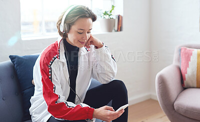 Buy stock photo Beautiful woman using smartphone listening to music on mobile phone wearing headphones sitting on sofa at home