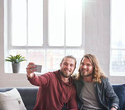 Buy stock photo twin brothers taking photo using smartphone sitting on sofa at home