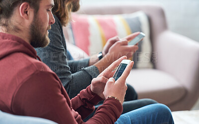 Buy stock photo Young man using smartphone browsing social media texting messages sitting on sofa with friend