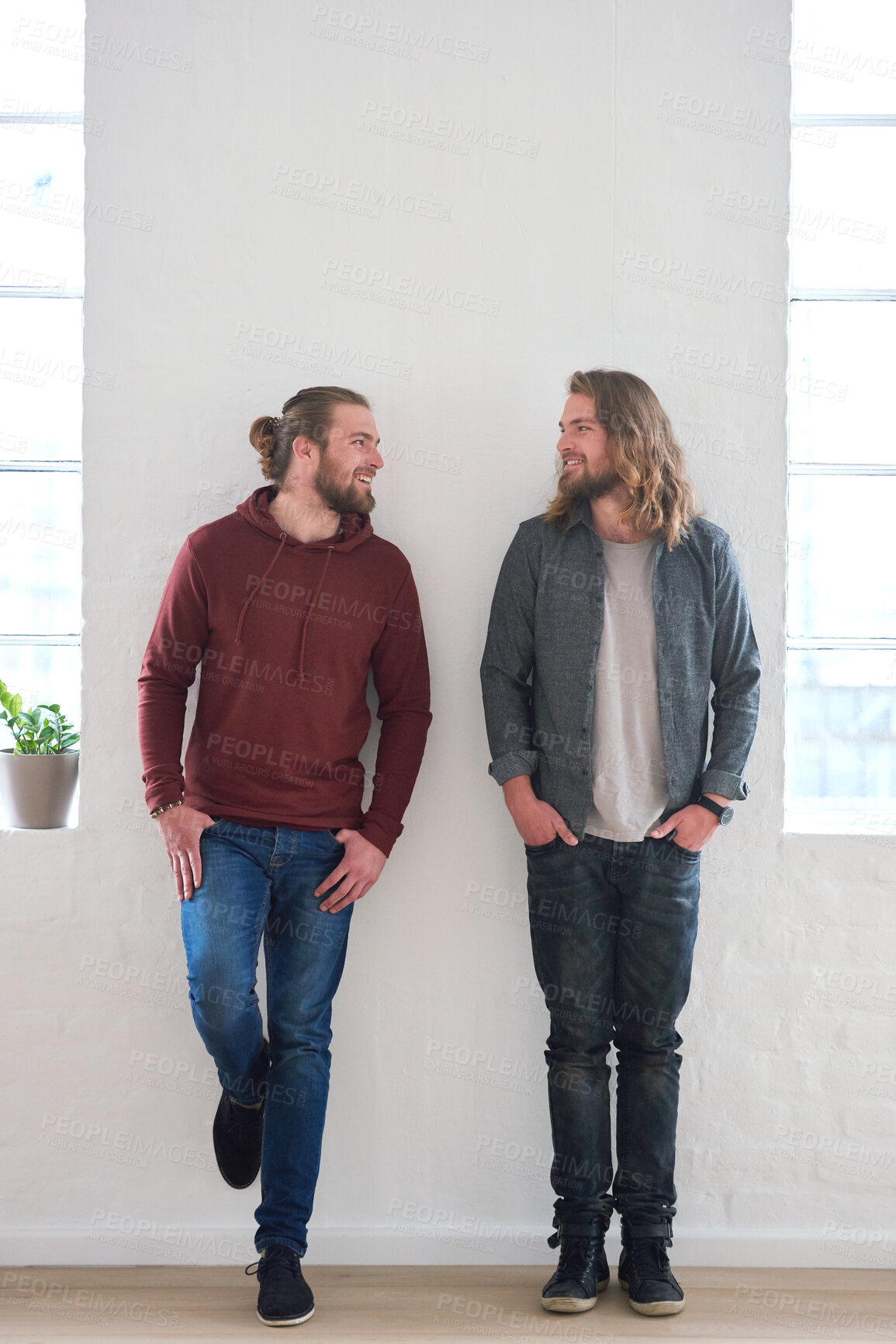 Buy stock photo Family, smile and happy twins standing together with happiness in a home. Young smiling and identical male sibling people in a house by a wall showing identity features looking hipster and gen z