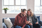 twin brothers using smartphone browsing internet on mobile phone sitting on sofa at home