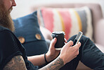 hipster man using smartphone browsing messages on social media texting on mobile phone holding coffee