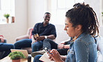 Young woman using smartphone browsing messages on social media texting on mobile phone sitting on sofa hanging out with friends