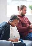 African american woman writing notes female student brainstorming listening to music wearing headphones