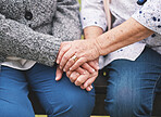 Two elderly women sitting on bench in park holding hands happy life long friends enjoying retirement