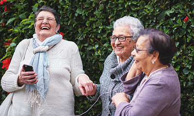 Buy stock photo Laughing, senior women and friends with music outdoor in a park with funny joke and happy. Headphones, group and garden with phone with audio and comedy with smile together in retirement on mobile