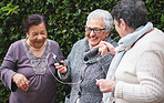 Happy old women listening to music on smartphone wearing earphones smiling enjoying fun celebrating retirement together outdoors