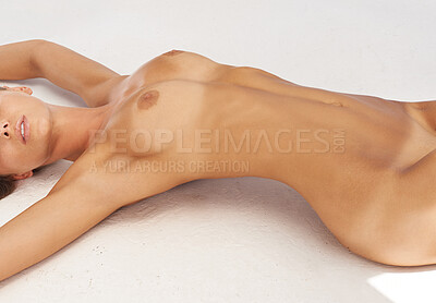 Buy stock photo Cropped shot of a naked woman lying on a white surface with her arms stretched and her back arched