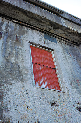 Buy stock photo A stone building with a red door on an old deserted property. Architecture details of the exterior of a grey industrial built structure. Weathered concrete walls with a high up wooden doorway