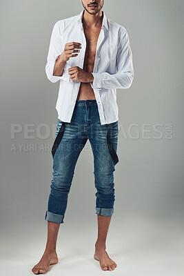 Buy stock photo Studio shot of a handsome young man wearing jeans and a white shirt against a grey background
