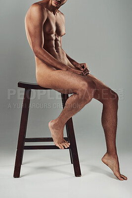 Buy stock photo Studio shot of a handsome young man sitting on a chair in the nude against a grey background